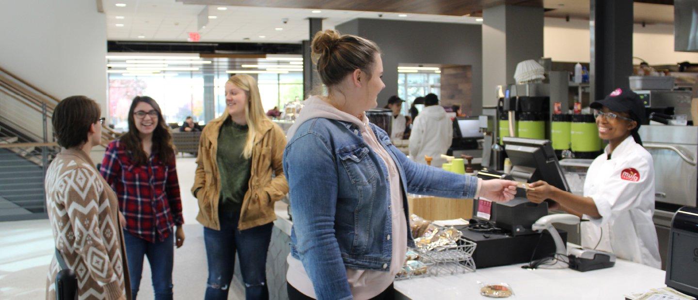 woman handing a card over a counter to a cashier in a dining center